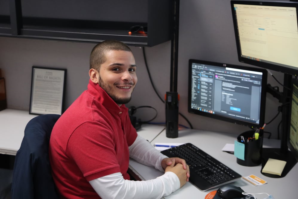 IT employee smiling and working at desk