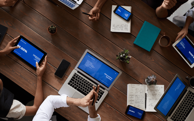 employees sitting at a conference table with technology