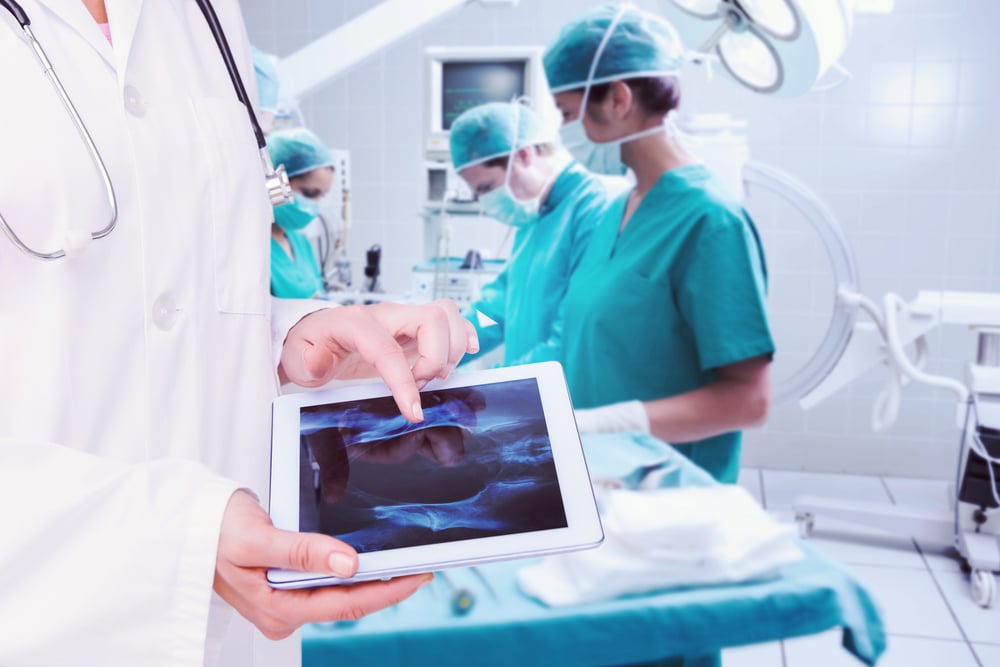 Composite image of doctor looking at xray on tablet