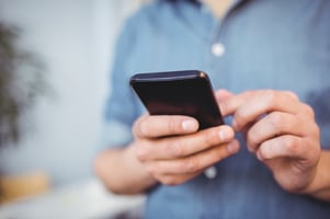 Midsection of businessman texting on cellphone while standing at creative office-1