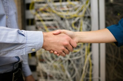 Technicians shaking hands in server room at the data centre